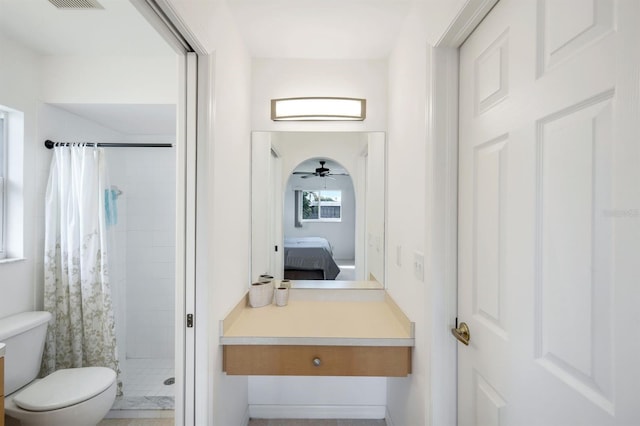 bathroom featuring toilet, ceiling fan, and a shower with curtain