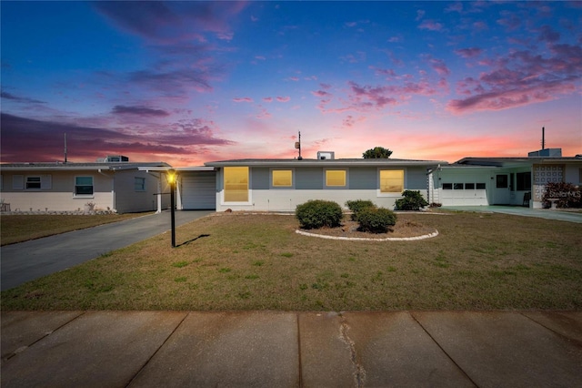 ranch-style home featuring a garage and a lawn