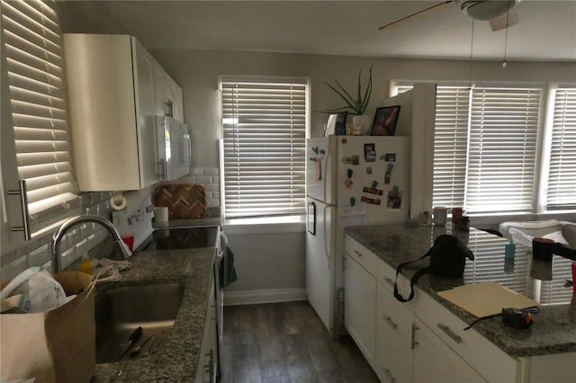 kitchen with white cabinetry, dark hardwood / wood-style floors, white appliances, and dark stone counters