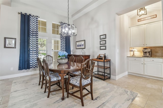 dining room featuring a towering ceiling, stone tile floors, baseboards, and a notable chandelier