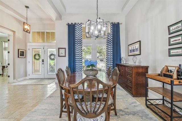 dining room featuring a chandelier, a high ceiling, plenty of natural light, and stone tile floors