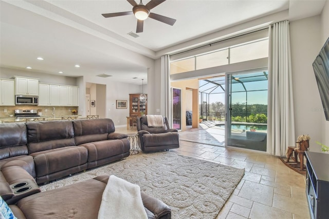 living area with ceiling fan, recessed lighting, stone tile floors, a sunroom, and baseboards