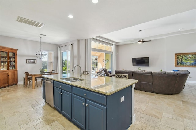 kitchen with a sink, blue cabinetry, visible vents, and stone tile flooring