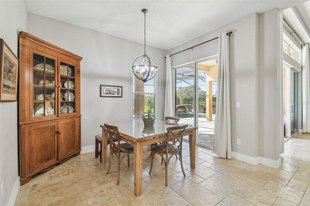 dining area with a chandelier, stone tile flooring, and baseboards