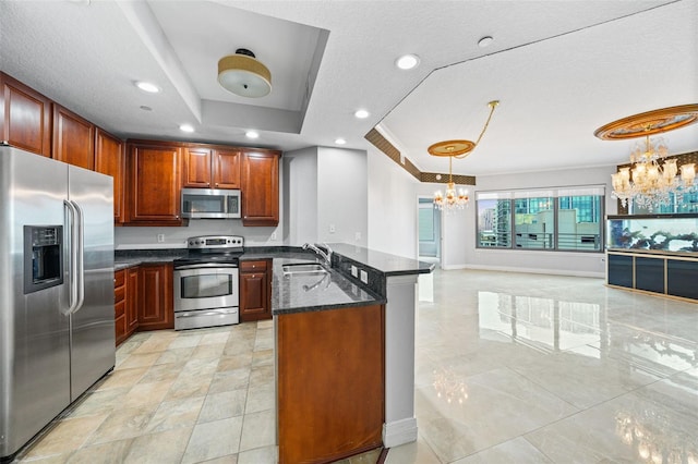kitchen with sink, hanging light fixtures, a tray ceiling, a notable chandelier, and stainless steel appliances