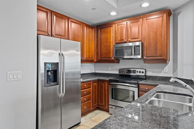 kitchen with appliances with stainless steel finishes, sink, and dark stone countertops