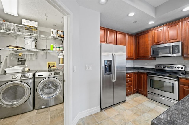 kitchen with appliances with stainless steel finishes, a textured ceiling, washer and dryer, and dark stone countertops