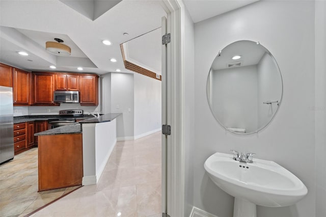 kitchen featuring stainless steel appliances, a raised ceiling, sink, and dark stone countertops