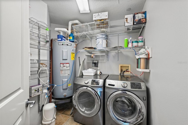 laundry area with washer and dryer, tile patterned floors, water heater, and a textured ceiling