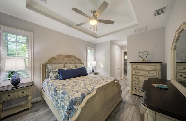 bedroom featuring multiple windows, a raised ceiling, and visible vents