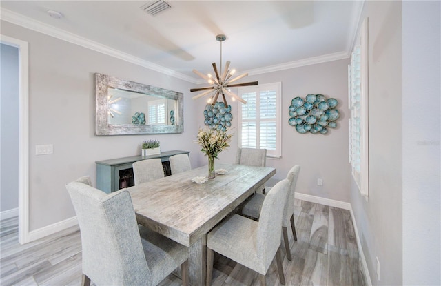 dining room featuring visible vents, ornamental molding, a chandelier, light wood-type flooring, and baseboards