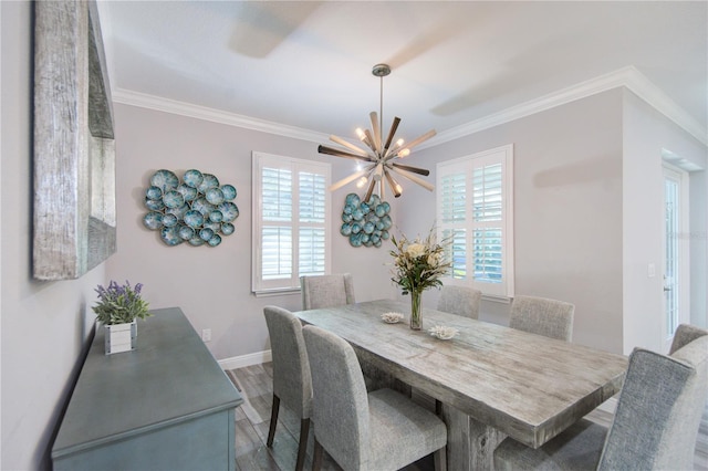 dining space with a chandelier, crown molding, baseboards, and wood finished floors