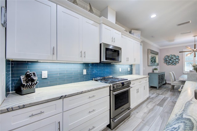 kitchen featuring stainless steel appliances, backsplash, ornamental molding, white cabinets, and light stone countertops