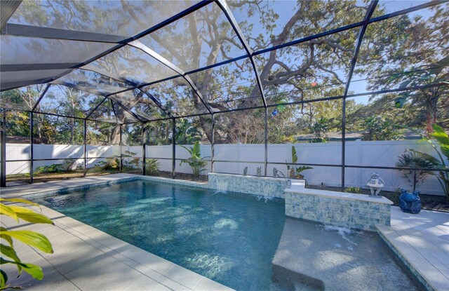 view of pool featuring glass enclosure, a patio area, a fenced backyard, and a fenced in pool