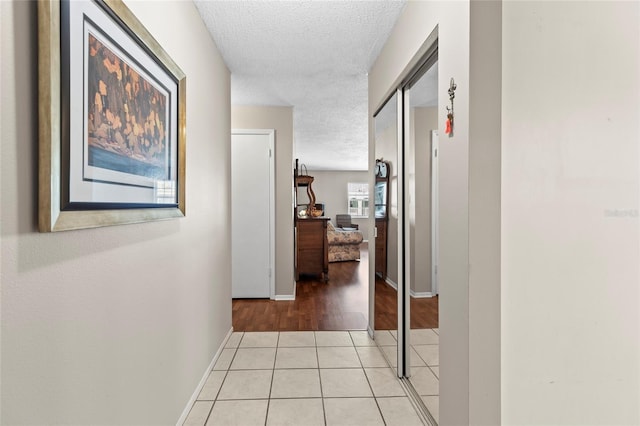 hall with light tile patterned floors and a textured ceiling