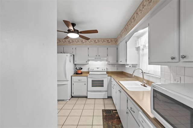 kitchen with light tile patterned flooring, white cabinetry, sink, backsplash, and white appliances