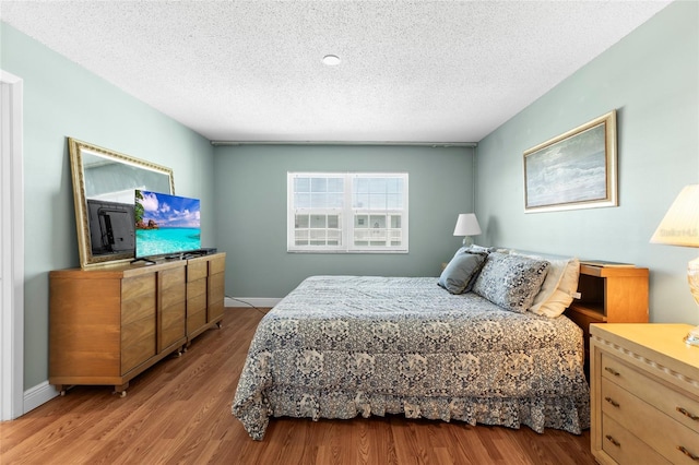 bedroom with light hardwood / wood-style floors and a textured ceiling