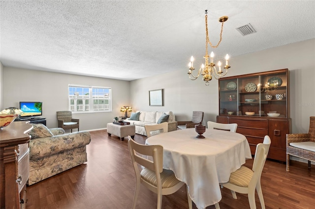 dining room with dark wood-type flooring, a chandelier, and a textured ceiling