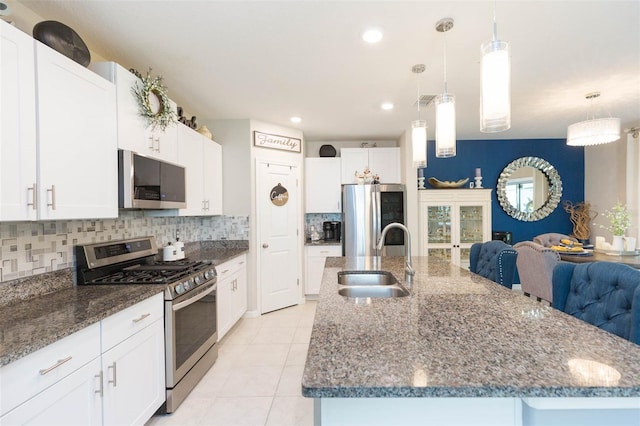 kitchen featuring pendant lighting, sink, stainless steel appliances, an island with sink, and white cabinets