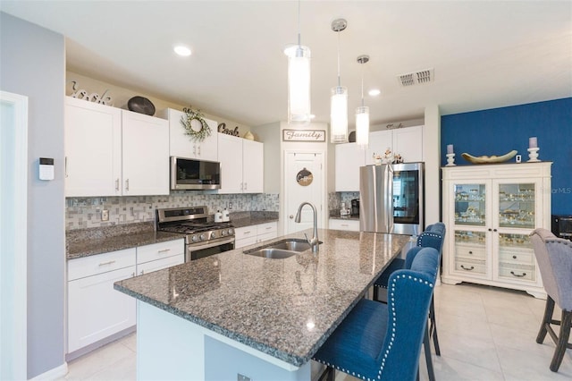 kitchen featuring an island with sink, appliances with stainless steel finishes, sink, and white cabinets