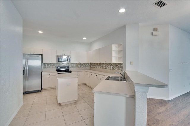 kitchen featuring sink, appliances with stainless steel finishes, backsplash, a center island, and kitchen peninsula