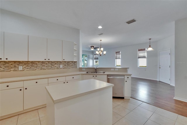 kitchen featuring sink, dishwasher, white cabinetry, hanging light fixtures, and a kitchen island