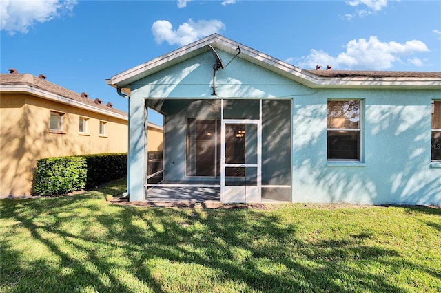 back of property featuring a lawn and a sunroom