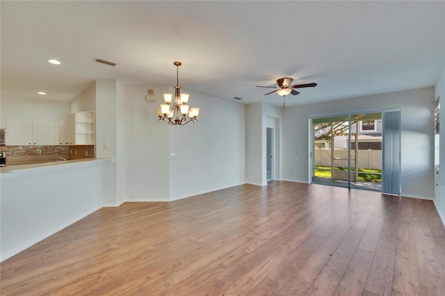 unfurnished living room featuring ceiling fan with notable chandelier and light hardwood / wood-style flooring