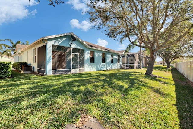 back of property with cooling unit, a yard, and a sunroom