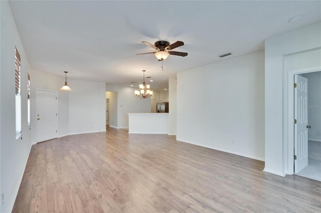 unfurnished living room with ceiling fan with notable chandelier and light wood-type flooring