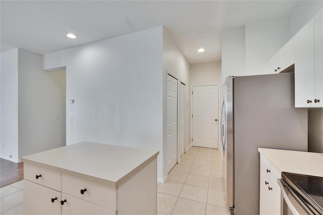 kitchen featuring light tile patterned floors, white cabinets, and stainless steel refrigerator