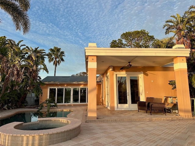 rear view of property featuring ceiling fan, a pool with hot tub, and a patio