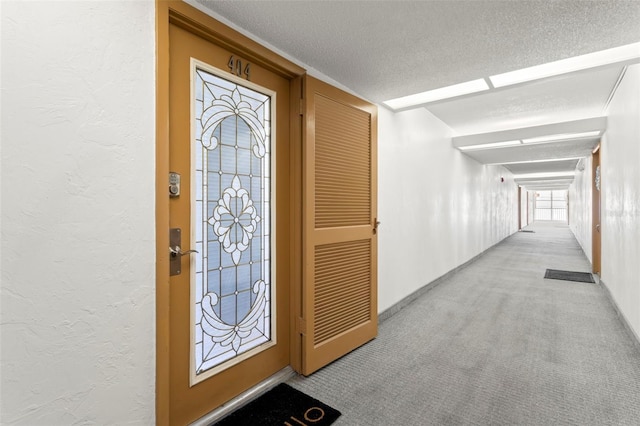 foyer featuring light carpet and a textured ceiling