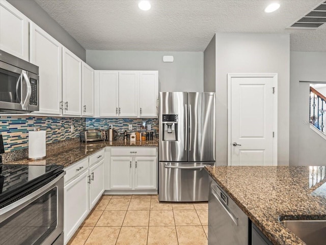 kitchen featuring white cabinetry, decorative backsplash, dark stone counters, and appliances with stainless steel finishes