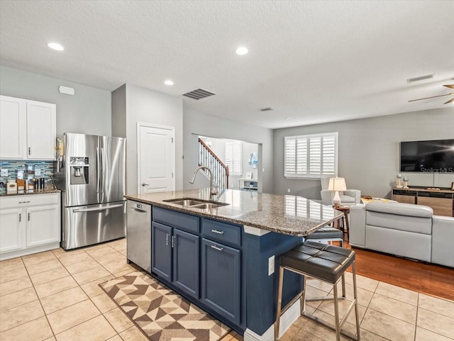 kitchen with sink, stone counters, white cabinetry, appliances with stainless steel finishes, and blue cabinets