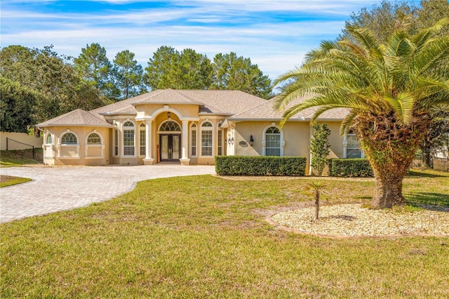 mediterranean / spanish-style home featuring a front lawn and french doors