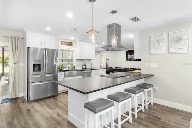 kitchen featuring pendant lighting, white cabinetry, island exhaust hood, kitchen peninsula, and stainless steel appliances