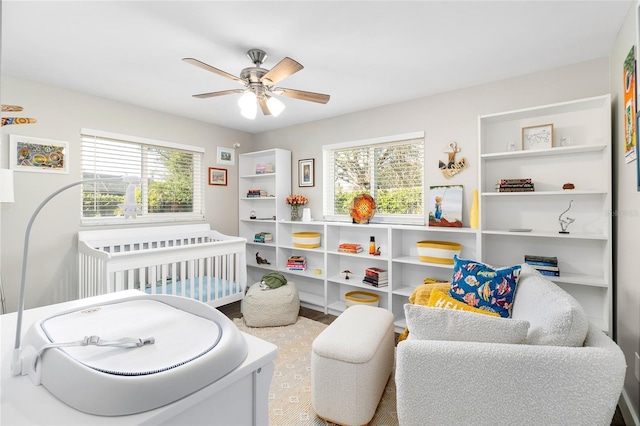 bedroom with ceiling fan, multiple windows, and a crib