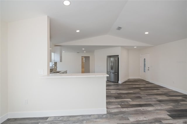 kitchen featuring lofted ceiling, sink, dark hardwood / wood-style floors, stainless steel fridge, and kitchen peninsula