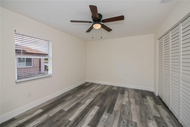 unfurnished bedroom with dark hardwood / wood-style flooring, a closet, and ceiling fan