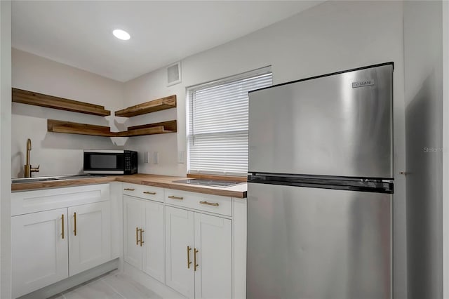 kitchen with white cabinetry, sink, stainless steel fridge, and stovetop