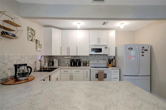 kitchen with sink, backsplash, white cabinets, and white appliances