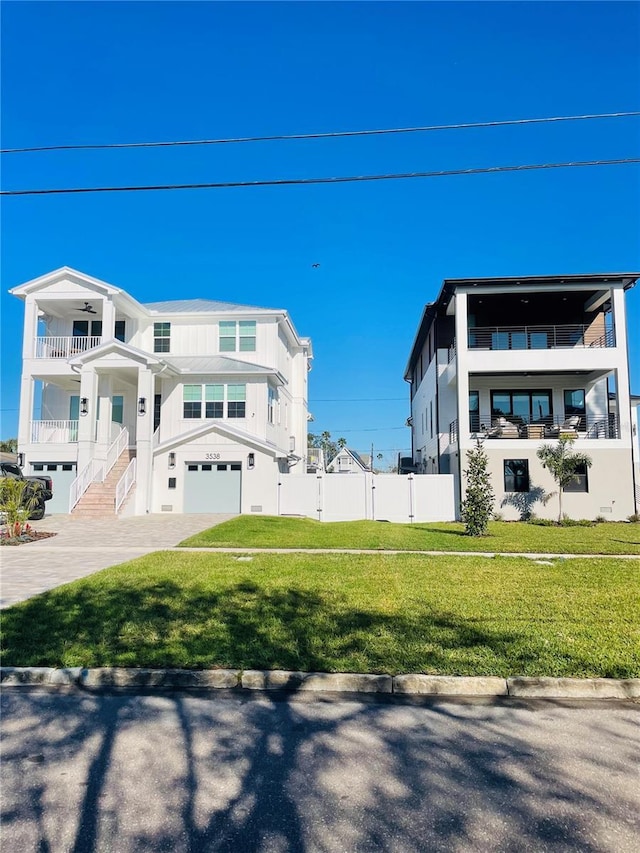 view of front of house with stucco siding, driveway, a front lawn, fence, and a garage