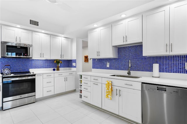 kitchen featuring light tile patterned flooring, white cabinetry, sink, backsplash, and stainless steel appliances