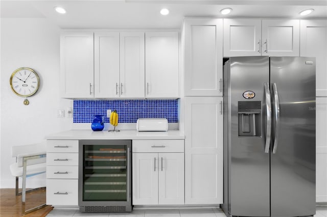 kitchen with backsplash, stainless steel fridge, beverage cooler, and white cabinets