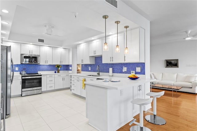 kitchen featuring stainless steel appliances, sink, ceiling fan, and decorative light fixtures