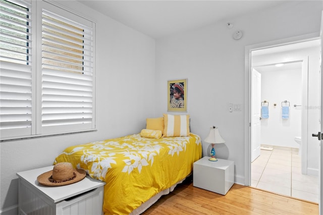 bedroom with ensuite bath and wood-type flooring