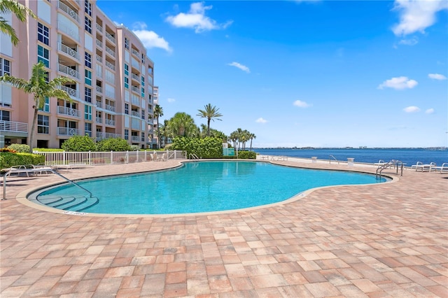 view of swimming pool with a patio area and a water view