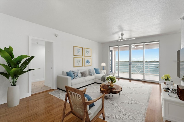 4993 Bacopa Ln S Unit 304, Saint Petersburg, FL 33715 - living area featuring light wood-style flooring, a ceiling fan, and a textured ceiling