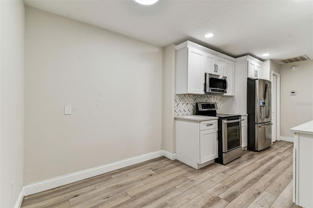 kitchen with decorative backsplash, stainless steel appliances, light hardwood / wood-style floors, and white cabinets